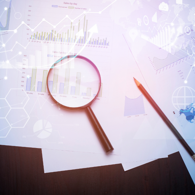 Magnifying glass and pen on a table over a series of graphs and charts.