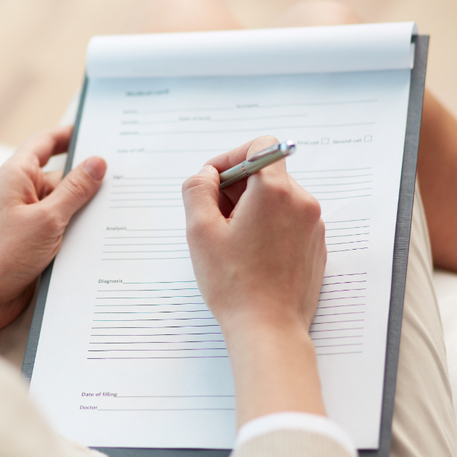 Person filling out a form on a clipboard.