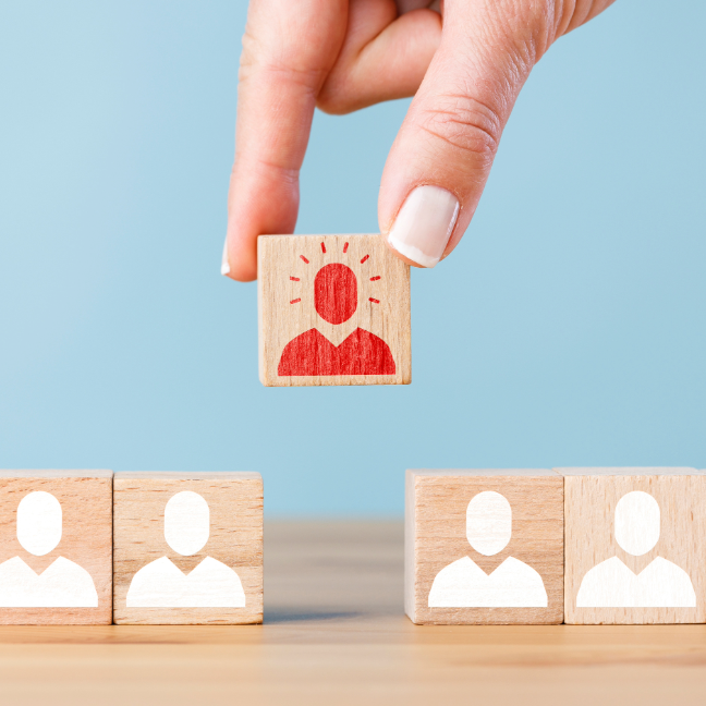 Person placing a block with an outline of a person in red amongst other blocks with people in white.