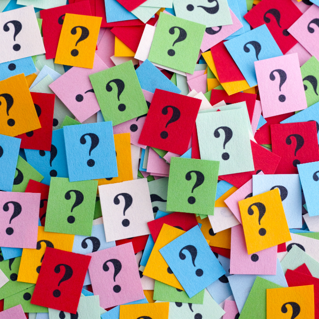 Multicoloured bits of paper with a question mark written on each.