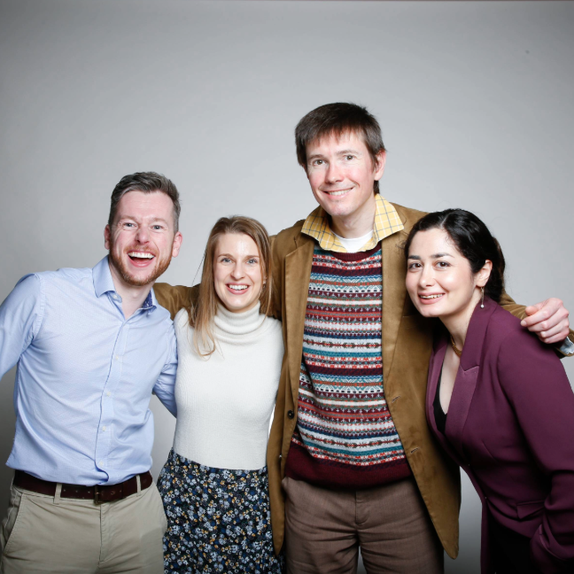 Four UK Young Academy members stand together laughing with their arms round eachother.