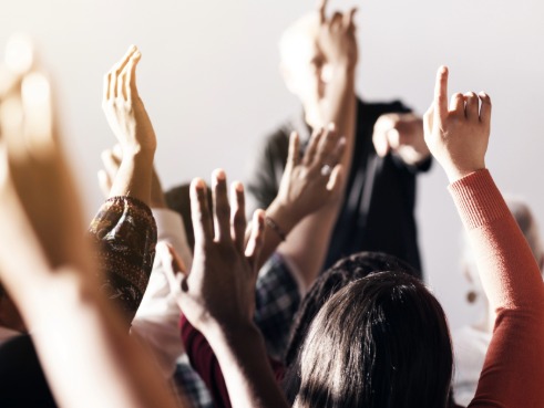 A person in classroom puts her hand up during a lesson