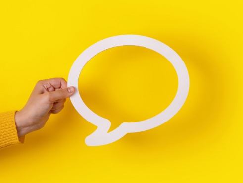 Person holding up a cutout speech bubble.