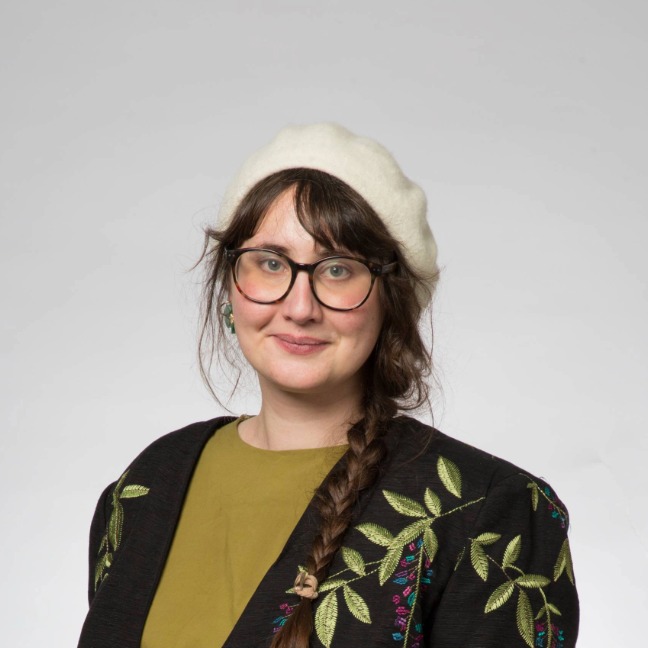 Woman with white beret and glasses smiles at camera