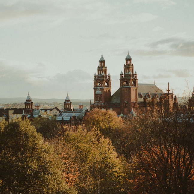 Glasgow University in Autumn a big gothic building surrounded by trees that are starting to turn orange