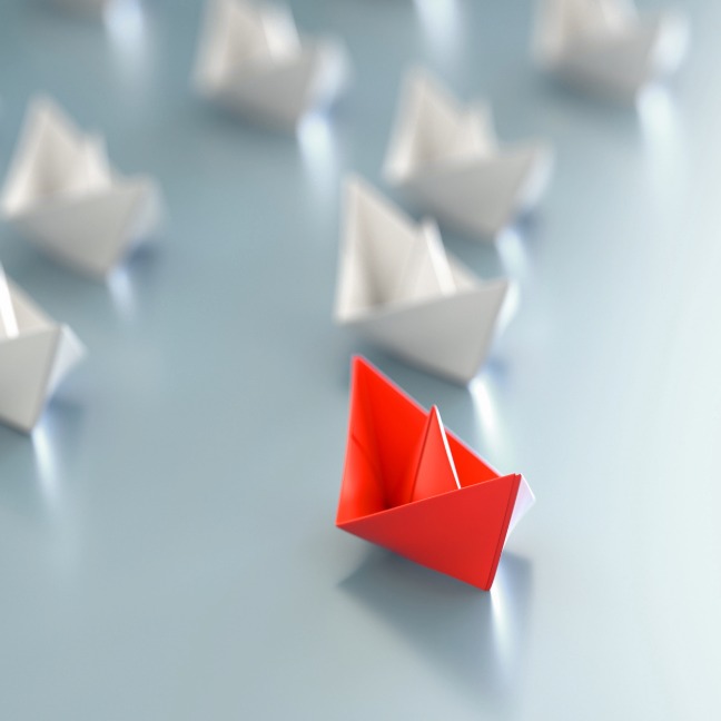 Collection of origami boats with front boat highlighted in red