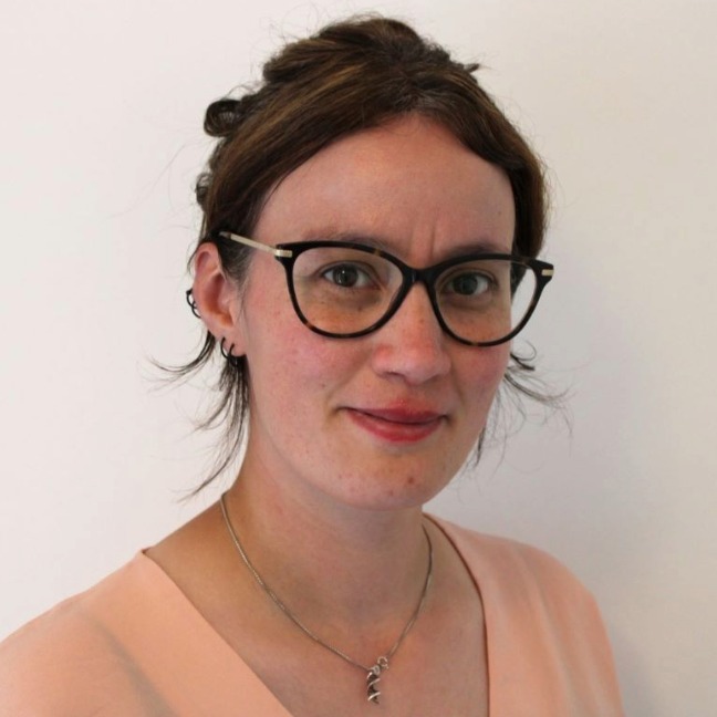 Woman in glasses smiles at camera
