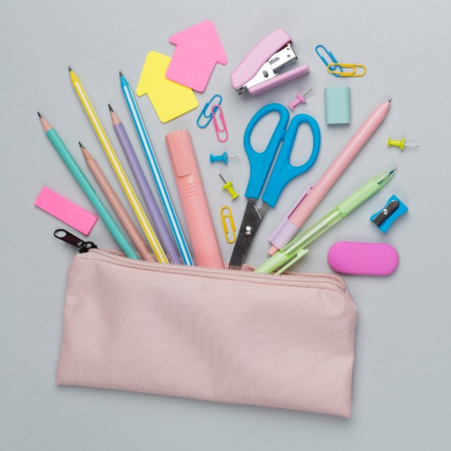 A pencil case open with pens, pencils, a stapler, Post-it Notes, paper clips, a sharpener, and staples spilling out.