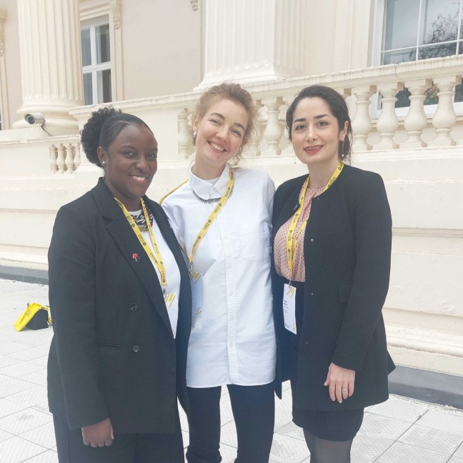 three members smile at the camera outside