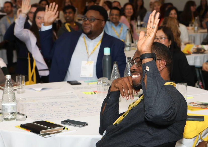 UK Young Academy members smile and laugh as they raise their hands to answer a question