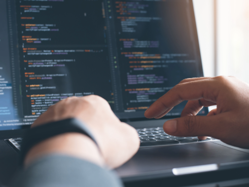 Someone types code on a laptop.