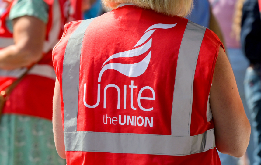 Person wearing a red Unite the Union high-visibility vest at an outdoor event, representing trade unions and employee representation.