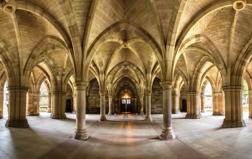 The University of Glasgow's historic cloisters, showing vaulted Gothic arches, stone columns, and a symmetrical corridor extending through the building.